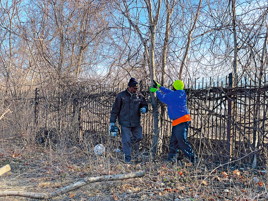 KC Parks employees and local volunteers remove brush from iron fence surrounding the reservoir in Kessler Park, Tuesday February 15. Photos By Abby Hoover