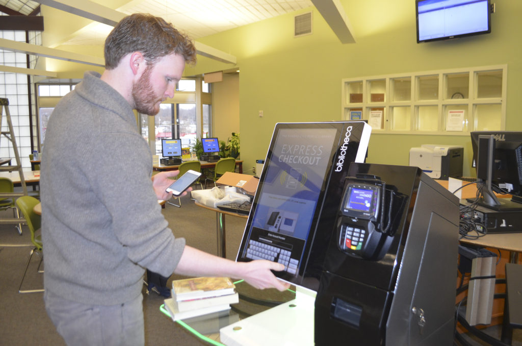 Kansas City Public Library Delivery Services Supervisor Mick Cottin demonstrates the North-East branch's new checkout system on Thursday, Feb. 23.