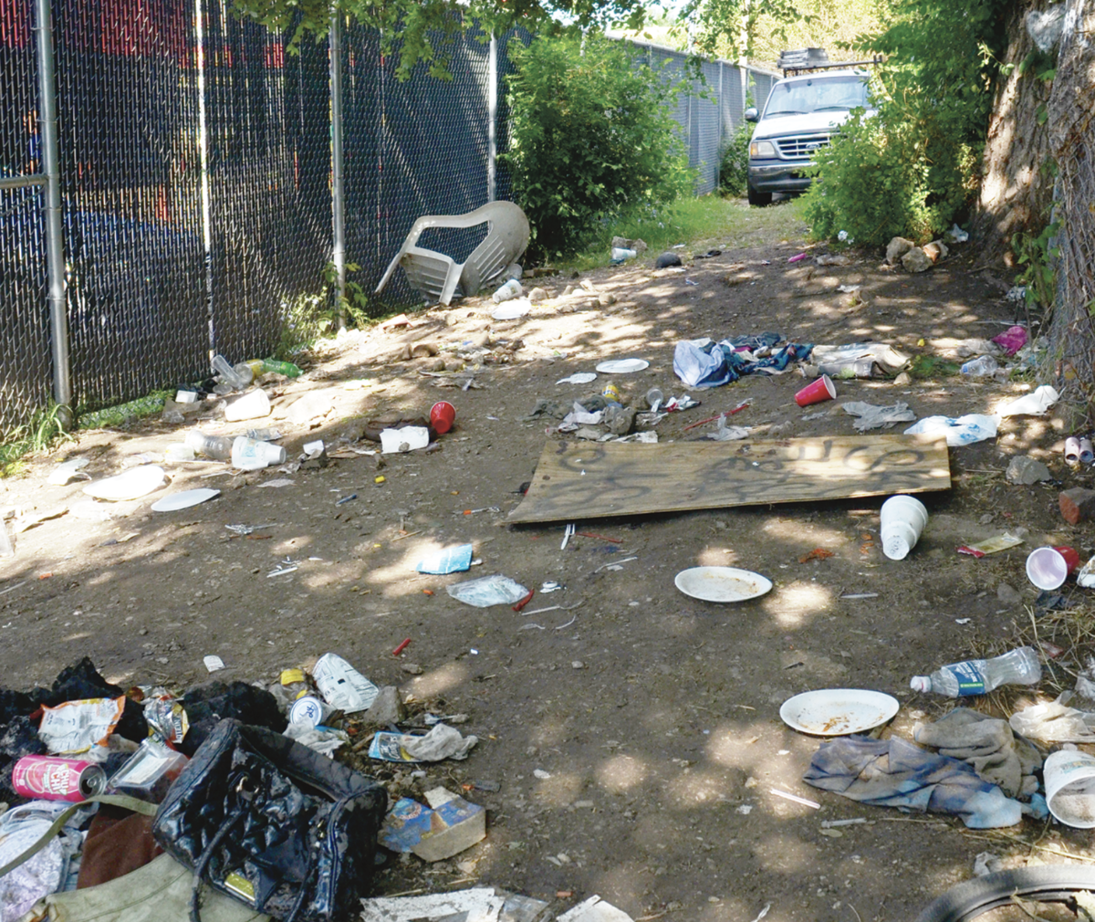 Alleyway strewn with trash, plates and cups